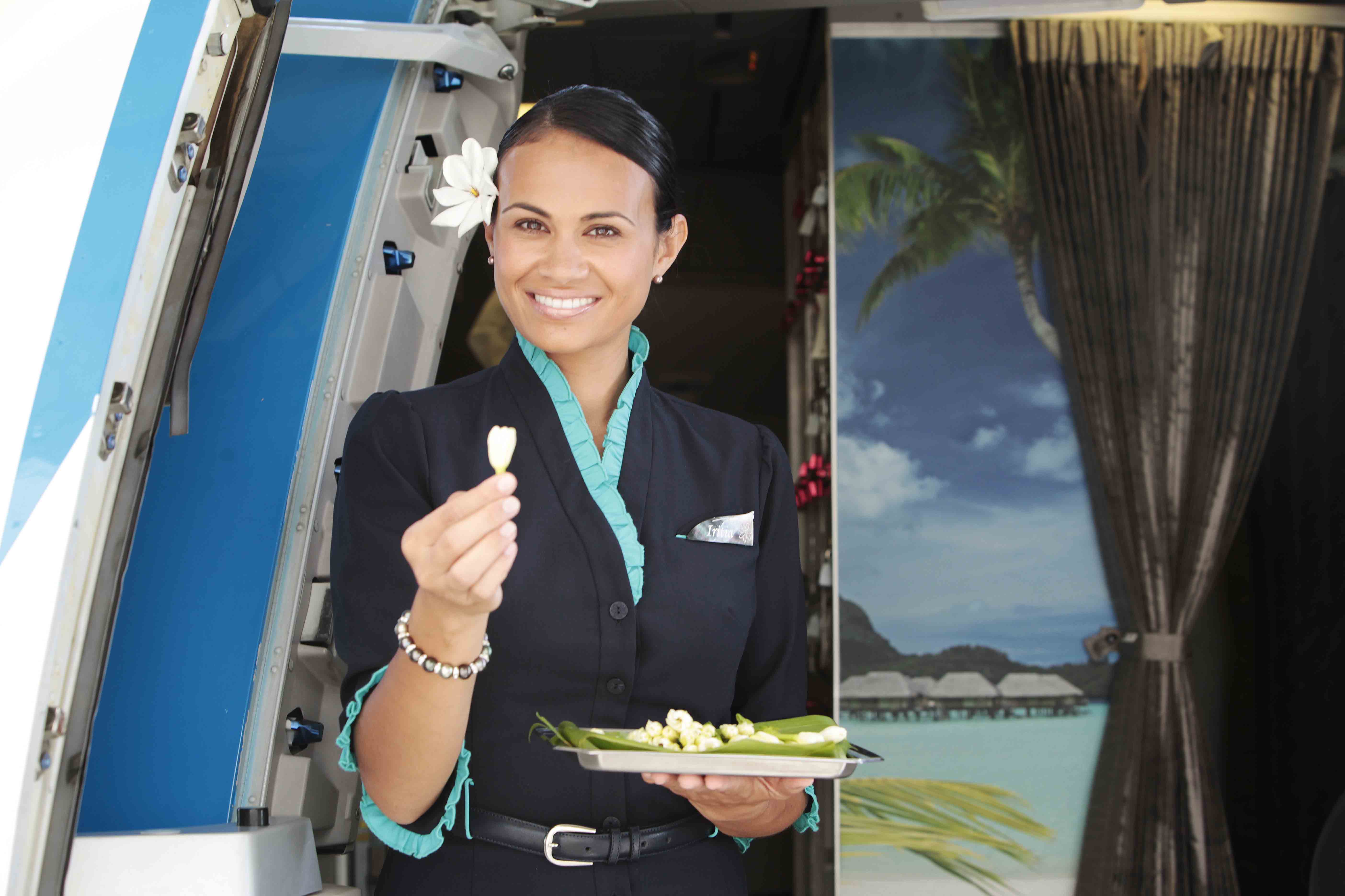 Comissária da Air Tahiti Nui oferecendo a flor símbolo do Tahiti, tiare, aos passageiros | foto: divulgação